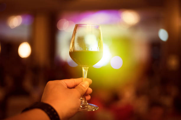 Hand holding red wine glass on bright light background