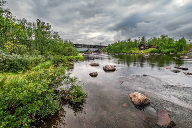 istock Fast-flowing creek in Swedish Lapland with iron ore train on bridge 1172640572