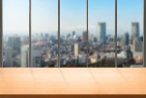 Wood table in city center modern office background with empty copy space on the table for product display mockup. Workspace desk interior and place for corporate business.