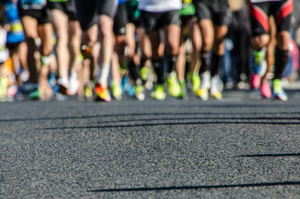 Asphalt with legs bottom of runners during the marathon of Valencia Asphalt with legs bottom of runners during the marathon of Valencia marathon stock pictures, royalty-free photos & images