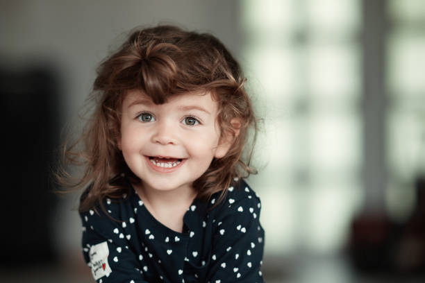 Brunette baby girl inside the house, having her hair messy and face covered, smiling and feeling hapy