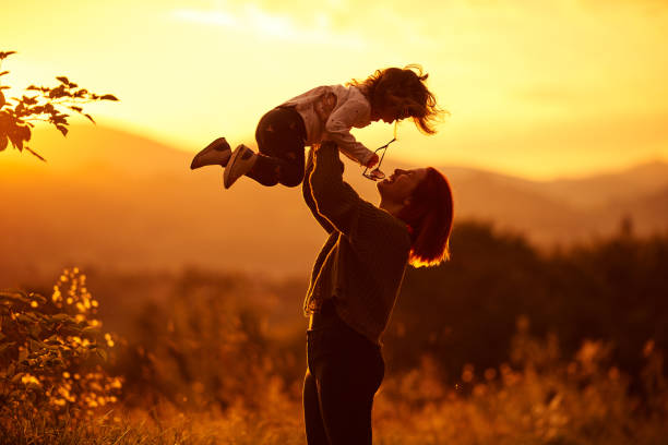 Red haired mother picking up her little baby girl