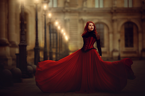 Red-haired fashion model in old fashioned dress posing in France