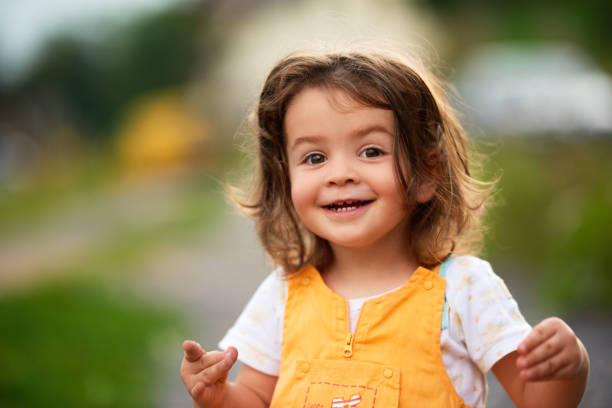 Little girl with brown hair outdoors, looking at the camera happily