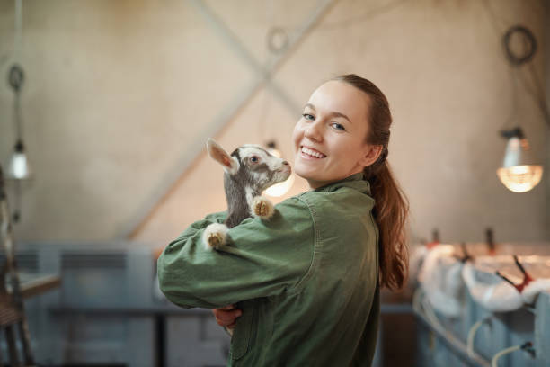 I guess you could call him my kid Shot of a young woman holding an adorable baby goat at a dairy farm goat pen stock pictures, royalty-free photos & images