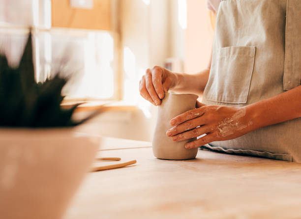 istock Hands of unrecognizable potter molding a mug at desk 1172654944