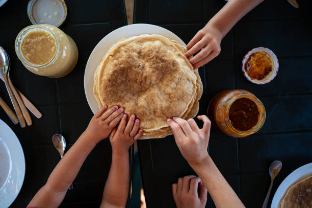 Kids reaching for crepes at breakfast Top view of kids reaching for crepes at a breakfast table. crêpe pancake photos stock pictures, royalty-free photos & images