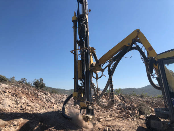 la maquinaria amarilla está perforando agujeros en la parte superior del acantilado de mar rocoso durante las operaciones de perforación de agujeros de explosión - drill mining rock borehole fotografías e imágenes de stock