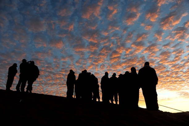 silhouette des personnes devant le ciel rose de dapple au coucher du soleil - brain wash photos et images de collection