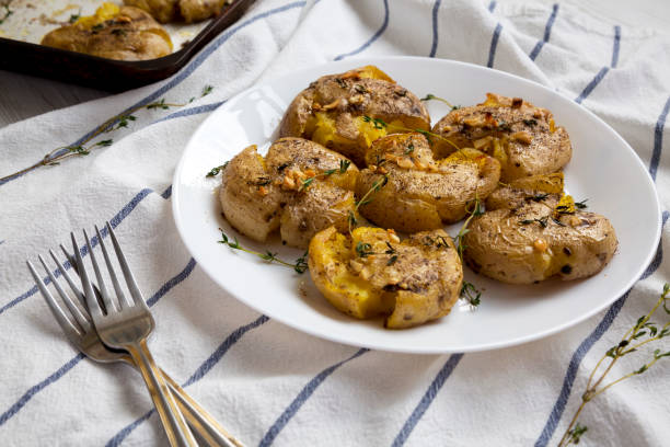istock Homemade garlic thyme smashed potatoes on a white plate, low angle view. Close-up. 1172665373