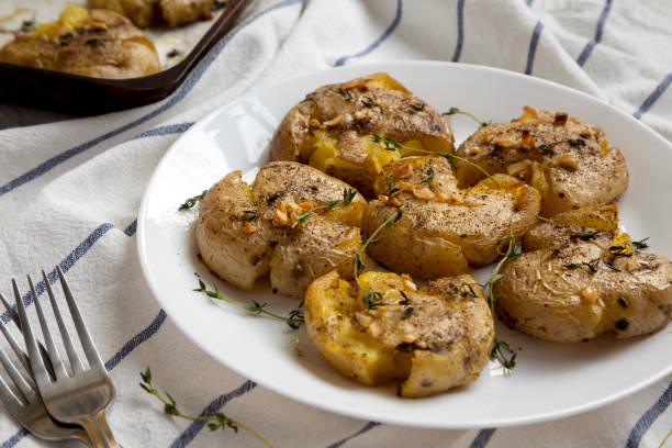 istock Homemade garlic thyme smashed potatoes on a white plate, side view. Close-up. 1172665413