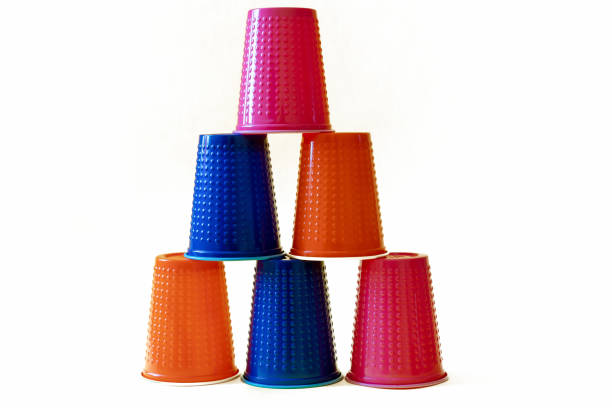 istock Multi-colored blue, orange and pink plastic cups on a white background. Tower wall made of plastic glasses. Plastic pollution concept. 1172666987