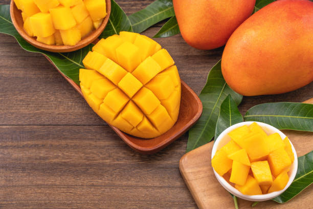 istock Fresh mango, beautiful chopped fruit with green leaves on dark wooden table background. Tropical fruit design concept. 1172667127