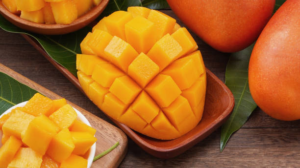 istock Fresh mango, beautiful chopped fruit with green leaves on dark wooden table background. Tropical fruit design concept. 1172667137