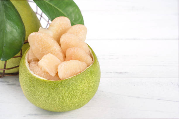 istock Fresh peeled pomelo, grapefruit, shaddock on bright wooden table background. Seasonal fruit for Mid-Autumn Festival, close up, copy space. 1172667250