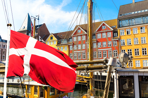 Vista icónica de Copenhague. Famoso puerto antiguo Nyhavn en el centro de Copenhague, Dinamarca durante el día soleado de verano con la bandera de Dinamarca en primer plano. photo