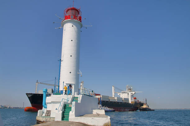 nowoczesny kontenerowiec pływających w pobliżu starej latarni morskiej w odessie. - industrial ship flash zdjęcia i obrazy z banku zdjęć