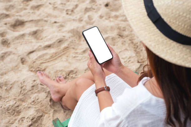 istock a woman holding black mobile phone with blank desktop screen while sitting on a beach chair 1172677234