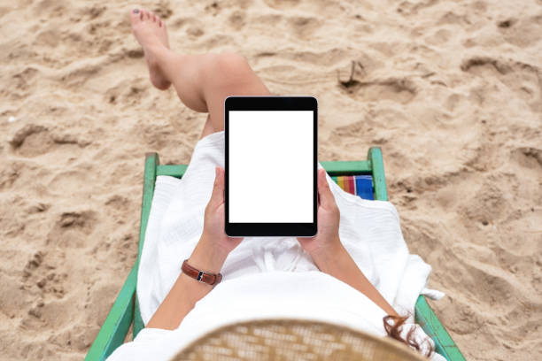 istock a woman holding and using a black tablet pc with blank desktop screen while laying down on a beach chair 1172677289