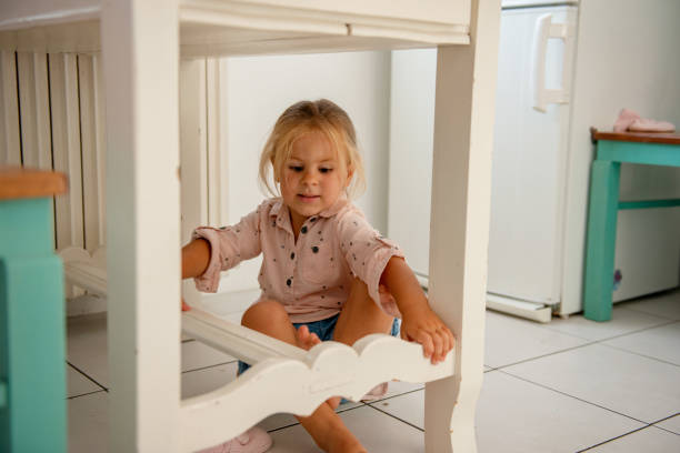 istock Little girl sits on the floor under the table 1172677974