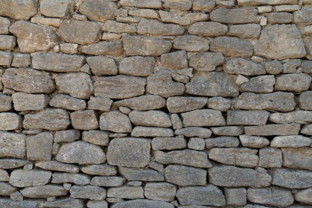Old gray wall made of large and small rectangular hewn natural stones Old gray wall made of large and small rectangular hewn natural stones roughhewn stock pictures, royalty-free photos & images