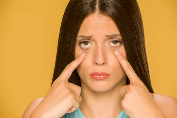 istock Young sad woman touching her  low eyelids on yellow background 1172681813