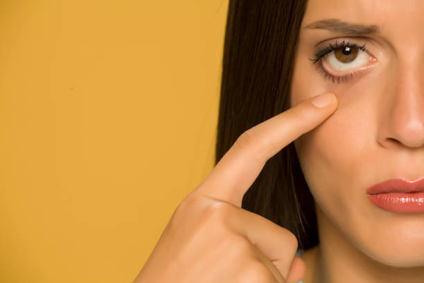 istock Young sad woman touching her  low eyelids on yellow background 1172681826