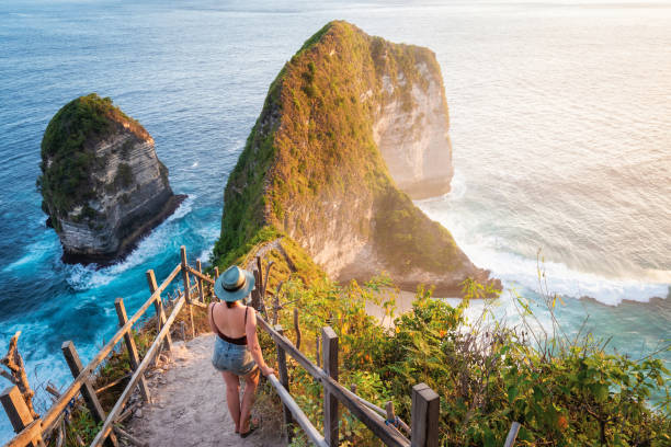 bali, indonésie, voyageur observant le coucher du soleil à la plage de kelingking dans l'île de nusa penida - nusa lembongan photos photos et images de collection