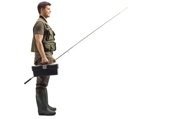 Full length profile shot of a fisherman smiling and standing with a rod and tool box isolated on white background