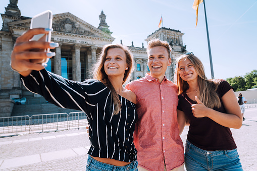 Smiling young people taking selfie against Reichstag Building in Berlin, Germany