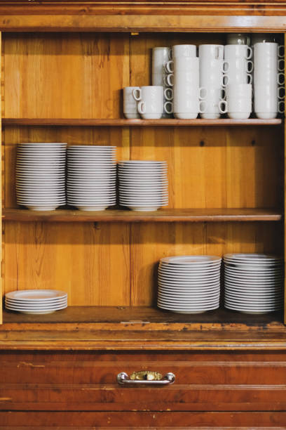 istock Vintage cupboard with dinnerware. old wooden kitchen cabinet with stack of white plates and cups. retro sideboard 1172685329