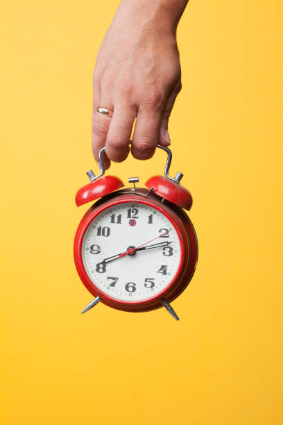 istock Hand holding a red watch on a yellow background 1172688492