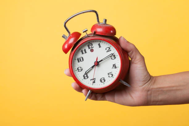 istock Hand holding a red watch on a yellow background 1172688497