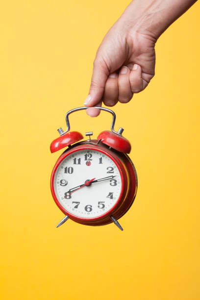 istock Hand holding a red watch on a yellow background 1172688510