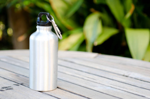 botella de agua reutilizable sobre una mesa de madera al aire libre - water bottle bottle steel stainless steel fotografías e imágenes de stock