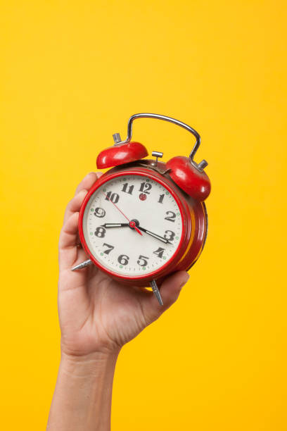 istock Hand holding a red watch on a yellow background 1172689797