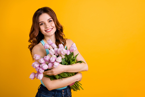 My best 8 march ever. Photo of pretty lady, holding pink tulips in hands women's day concept wear tank-top isolated yellow background