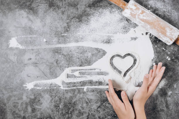 Baking background. Girl hands keep rolling pin and heart of flour on gray table with copy space, top view. Valentine's Day Baking background. Girl hands keep rolling pin and heart of flour on gray table with copy space, top view. Valentine's Day baking bread photos stock pictures, royalty-free photos & images