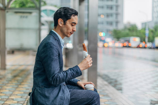 istock Modern businessman eating sandwich on bus stop 1172699116