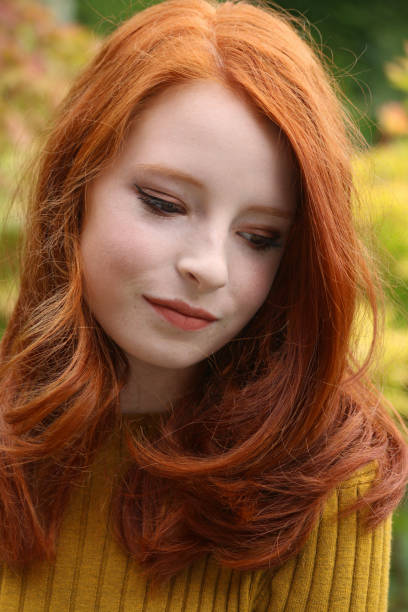 immagine dell'adolescente dai capelli rossi 14 /15 anni che modella il trucco autunnale, guardando verso il basso lontano dalla fotocamera, sfondo blurred colore foglia autunnale - human lips orange lipstick human mouth foto e immagini stock