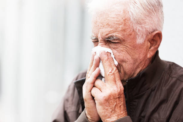 istock Senior man ill with flu blows his nose on a tissue 1172707396