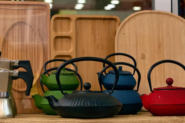Common type cast iron teapots in different colors (Green,Blue, Black and Red colors) displayed on a street vendor's pitch.