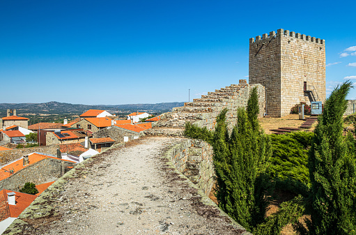Celorico da Beira, Portugal - August 15, 2018: View of the wall with the tower of Celorico da Beira castle in the background on a summer day with the blue sky. We can also see part of the historical area of the village.