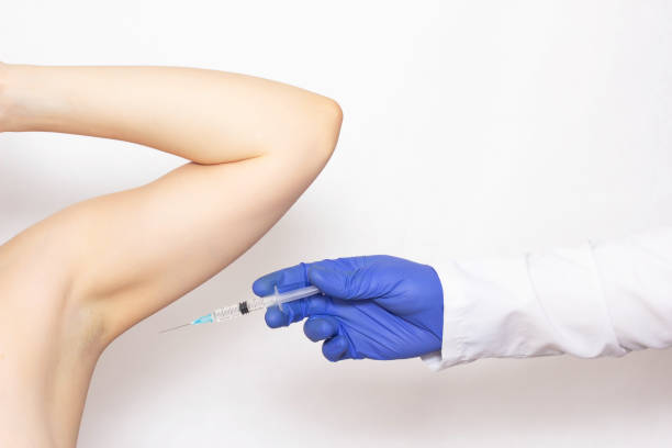Doctor makes an injection in the armpit of a girl against sweating and hyperhidrosis, white background, underarm, botulinum toxin, copy space Doctor makes an injection in the armpit of a girl against sweating and hyperhidrosis, white background, botulinum toxin sweat gland stock pictures, royalty-free photos & images