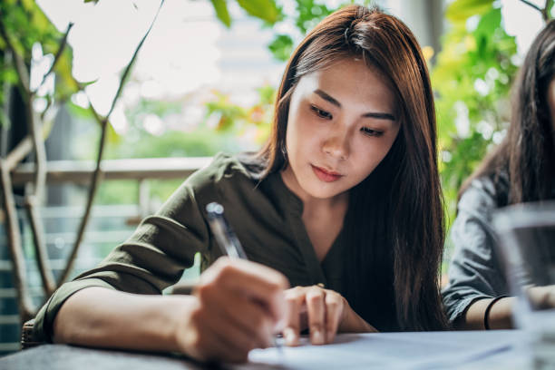istock Asian woman writing on paper 1172709356