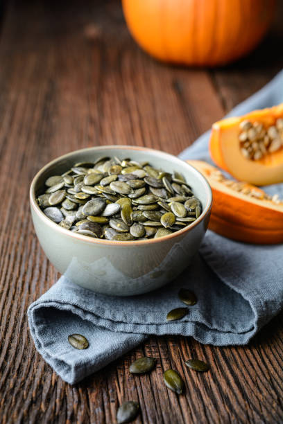 Pumpkin seeds in ceramic bowl, decorated with pumpkin slices stock photo
