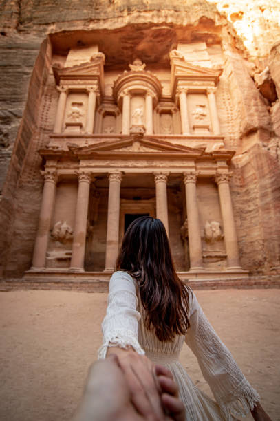 Asian woman tourist holding hand in Petra, Jordan Asian woman tourist in white dress holding her couple hand at Treasury or Al-khazneh, the ancient city of Petra, Jordan. Travel UNESCO World Heritage Site in Middle East jordan middle east photos stock pictures, royalty-free photos & images