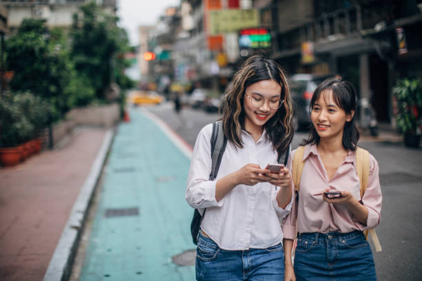 istock Two women students on the street downtown using smart phones 1172714238