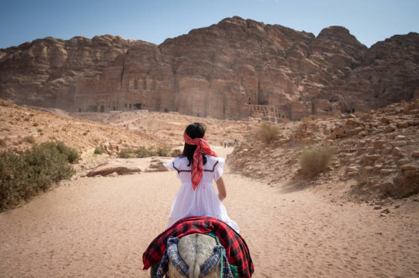 Asian woman tourist riding donkey in Petra, Jordan Asian woman tourist in white dress riding donkey in Petra ancient city of Jordan. Travel UNESCO World Heritage Site in Middle East. jordan middle east photos stock pictures, royalty-free photos & images
