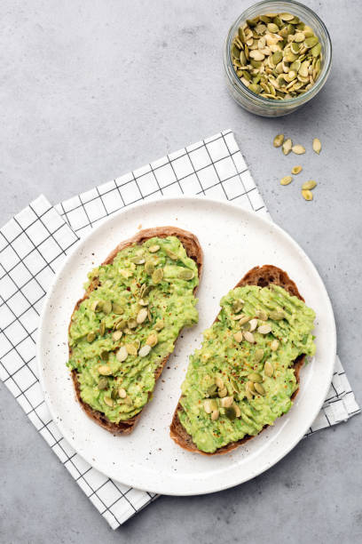 Healthy rye bread avocado toast with seeds Healthy rye bread avocado toast with seeds on white plate. Table top view crostini photos stock pictures, royalty-free photos & images